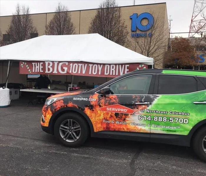 wrapped car in front of white tent with red 10tv big toy drive banner