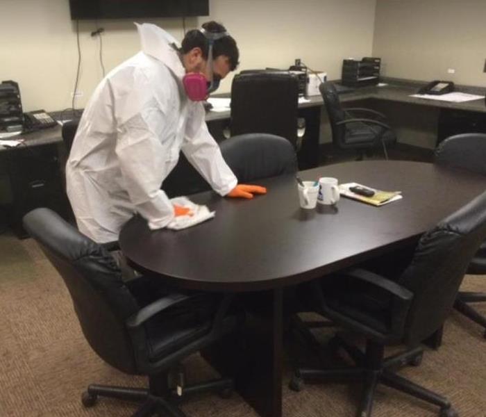 technician in hazmat suit wiping down table